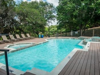 A swimming pool with deck chairs and trees in the background